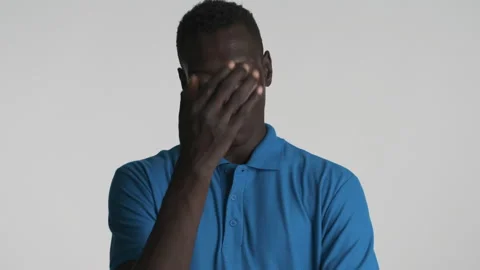 Young disappointed African American man covering face with hand waving head no